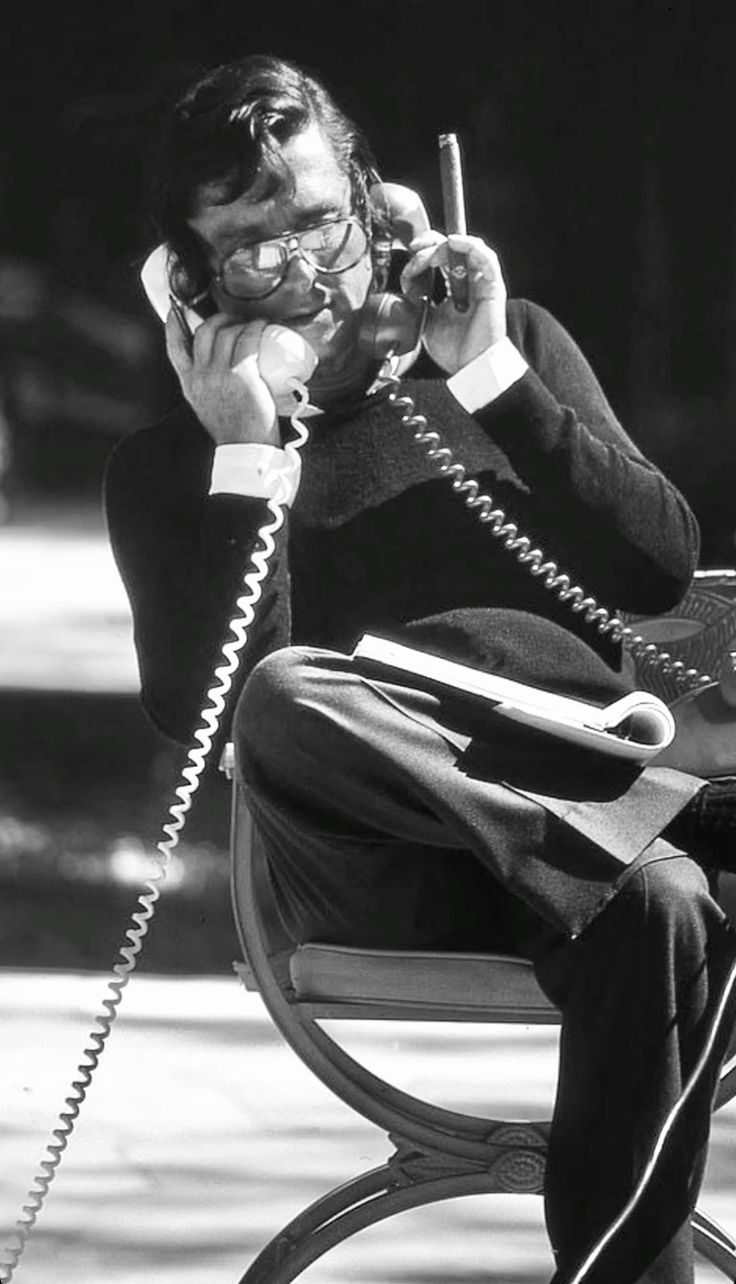 A man in deep concentration on a phone call, pen in hand