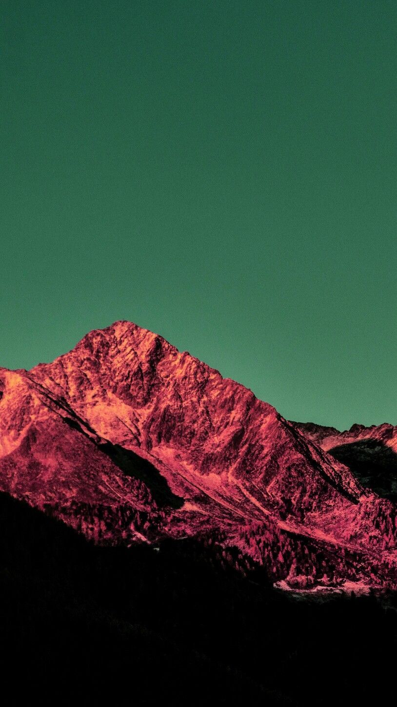 A mountain peak lit dramatically at dusk against a deep teal sky
