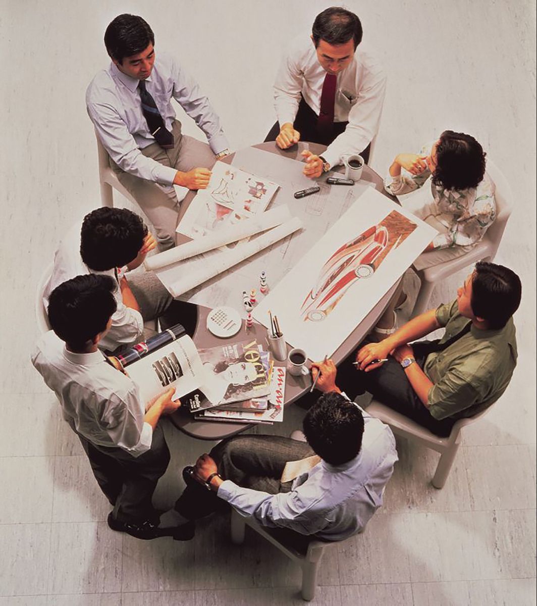 A team reviewing design work and drawings around a round table, seen from above