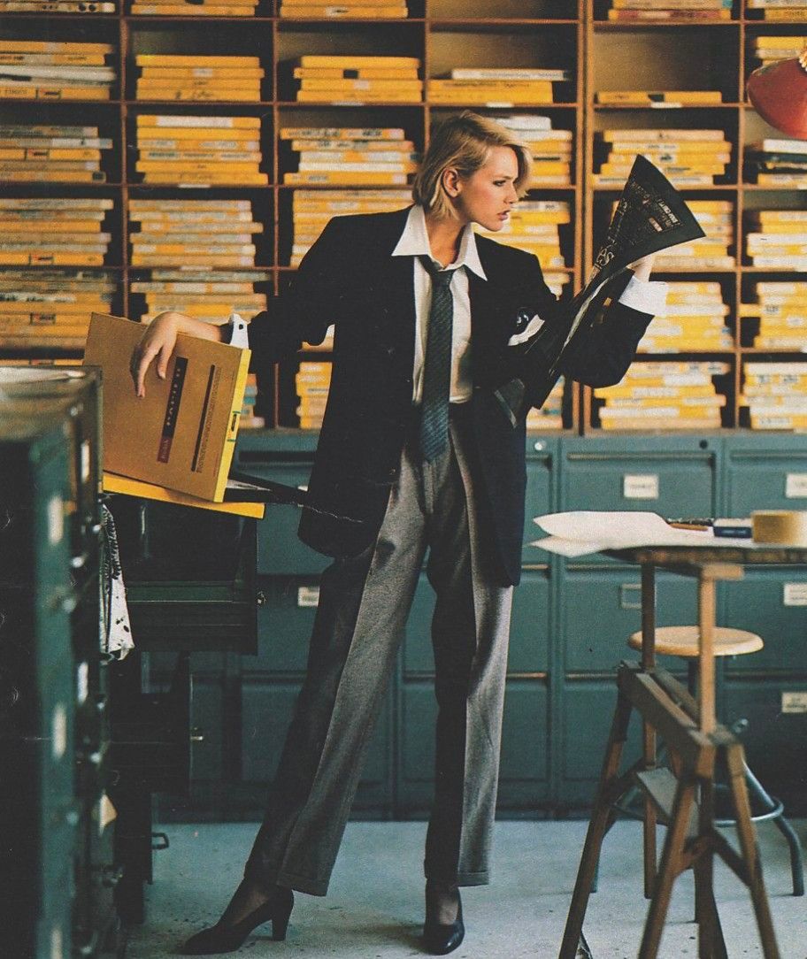 A woman in a suit reviewing documents in an archive room filled with labelled files