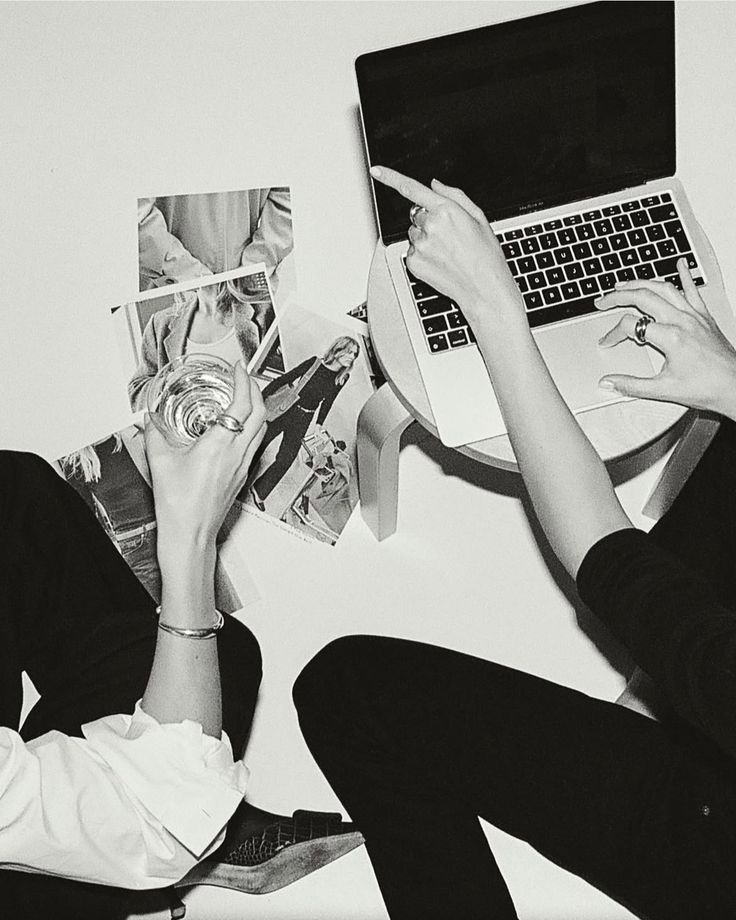 Two people working together with photos and a laptop, overhead view in black and white